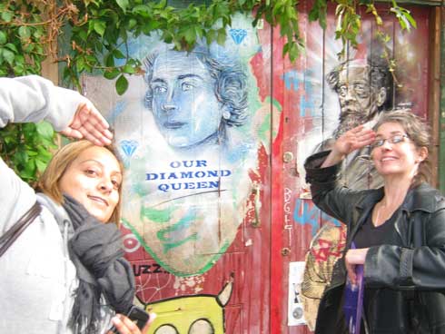 Two girls saluting an image of the Queen in London.