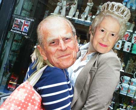 Two people wearing The Queen and Prince Philip masks on the streets of London.