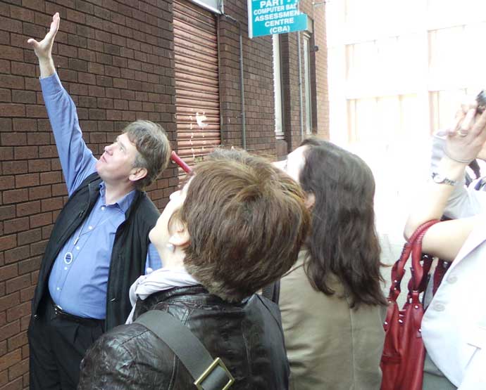 London tour guide Richard Jones pointing at the Little Dorrit pages that are on a wall in Southwark.